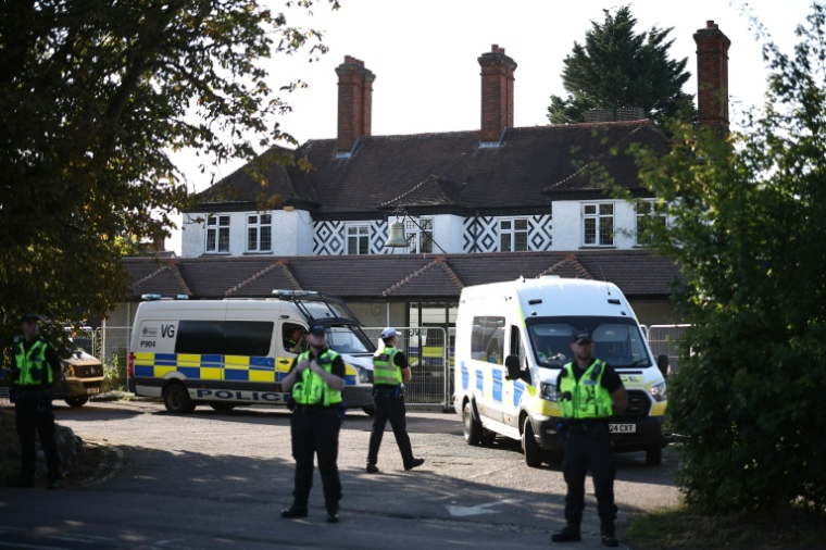 Des policiers devant l'hôtel Bell, censé héberger des demandeurs d'asile, à Epping, au nord-est de Londres, le 8 août 2025, alors que des manifestations de groupes d'extrême droite sont attendues  ( AFP / HENRY NICHOLLS )