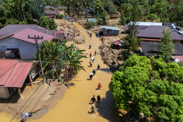Cette photo aérienne montre des villageois pataugeant dans la coulée de boue pour trouver un abri après les crues soudaines du village de Tukka, dans le district de Tapanuli central, province de Sumatra du Nord, le 3 décembre 2025 ( AFP / YT Hariono )