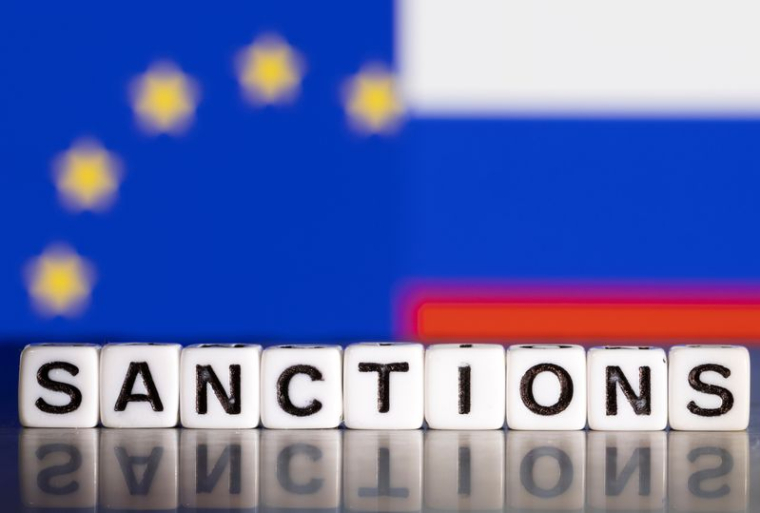 Des lettres en plastique formant le mot « Sanctions » devant les drapeaux de l'UE et de la Russie