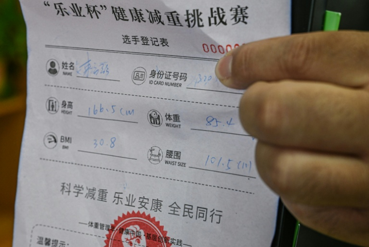 Un participant au programme minceur "Perdez du gras, gagnez du boeuf" montre  un formulaire affichant ses mensurations dans un centre communautaire de Wuxi, dans la province du Jiangsu, le 23 mars 2026 dans l'est de la Chine ( AFP / Jade GAO )