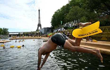 Un baigneur plonge dans la Seine sur un site aménagé sur le bras de Seine de Grenelle, près de la tour Eiffel (en arrière-plan), à Paris, le 5 juillet 2025 ( AFP / JULIEN DE ROSA )