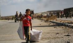 Un garçon palestinien porte un sac et traîne un autre derrière lui alors qu'il revient d'un point de distribution alimentaire dans le centre de la bande de Gaza, le 5 octobre 2025 ( AFP / Eyad BABA )