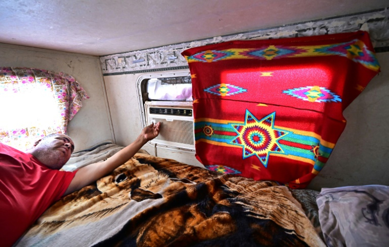 Elbert Yazzie règle son climatiseur dans sa caravane, après l'installation récente de l'électricité sur son terrain à Tuba City, en Arizona, le 8 juillet 2025 ( AFP / Frederic J. BROWN )