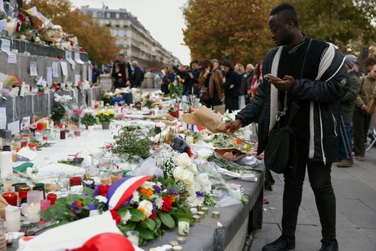 Un homme dépose des fleurs Place de la République à Paris le 13 novemvre 2025, en hommage aux victimes des attentats du 13 novembre 2015 ( AFP / Thomas SAMSON )