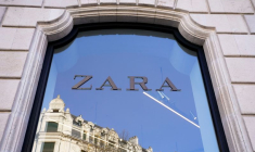 Un bâtiment se reflète dans la vitrine d'un magasin de vêtements Zara à Bilbao