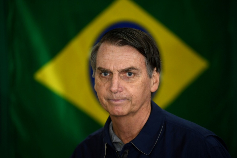 Jair Bolsonaro passe devant un drapeau brésilien dans un bureau de vote de Rio de Janeiro le jour de l'élection présidentielle, le 7 octobre 2018 ( AFP / Mauro PIMENTEL )