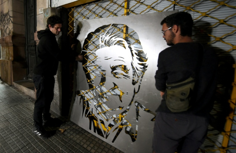 Deux jeunes préparent une fresque de l'ancien président uruguayen José "Pepe" Mujica le 13 mai 2025 à Montevideo ( AFP / DANTE FERNANDEZ )