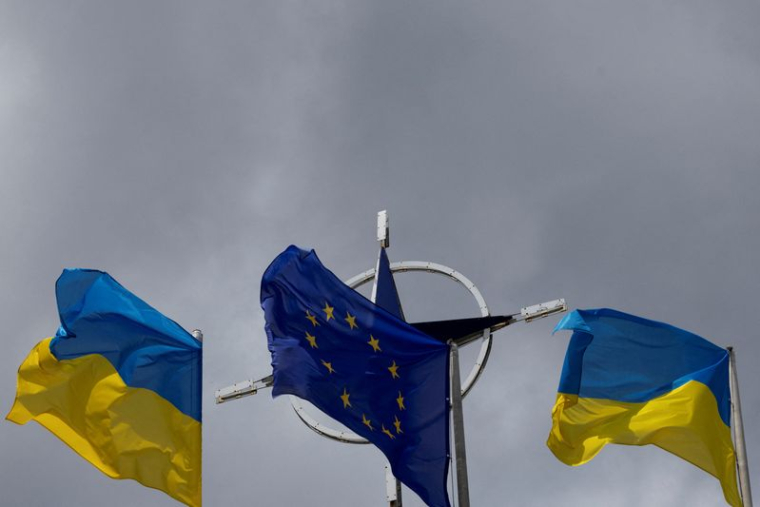 Photo d'archives des drapeaux de l'Ukraine et de l'UE  qui se dressent devant l'emblème de l'Otan au centre de Kyiv