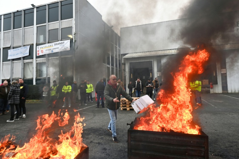 Un employé brûle des documents devant l'usine Brandt à Vendôme, le 11 décembre 2025 dans le Loir-et-Cher ( AFP / JEAN-FRANCOIS MONIER )