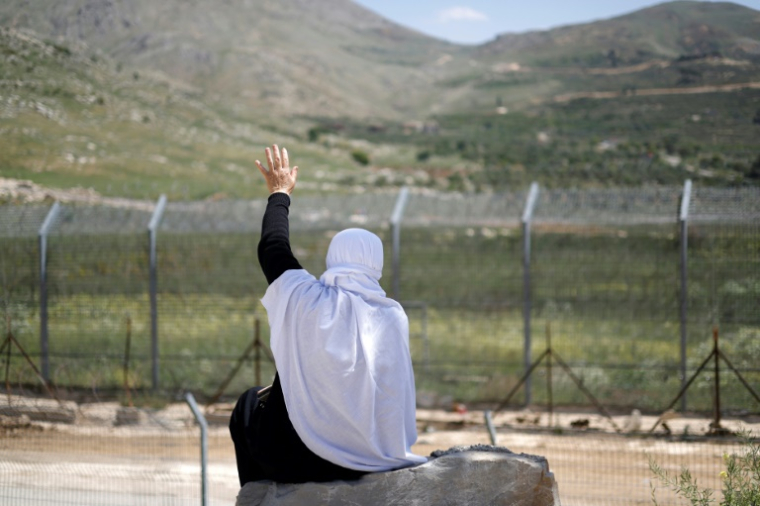 Une femme druze salue de la main des proches fuyant les violences près de Damas, après leur arrivée dans la zone tampon en face du village de Majdal Shams sur les hauteurs de la partie du Golan occupée par Israël, le 3 mai 2025 ( AFP / Jalaa MAREY )