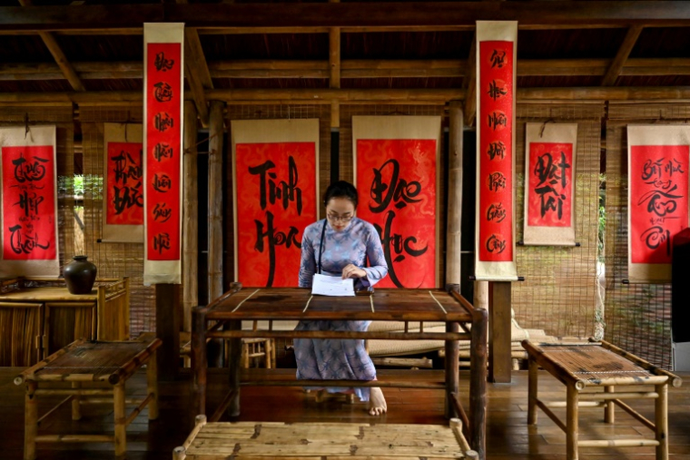 Une femme lit un document à la maison de calligraphie du Temple de la Littérature, dédié à l'ancien philosophe chinois Confucius, le 19 mai 2025 à Hanoï, au Vietnam ( AFP / Nhac NGUYEN )