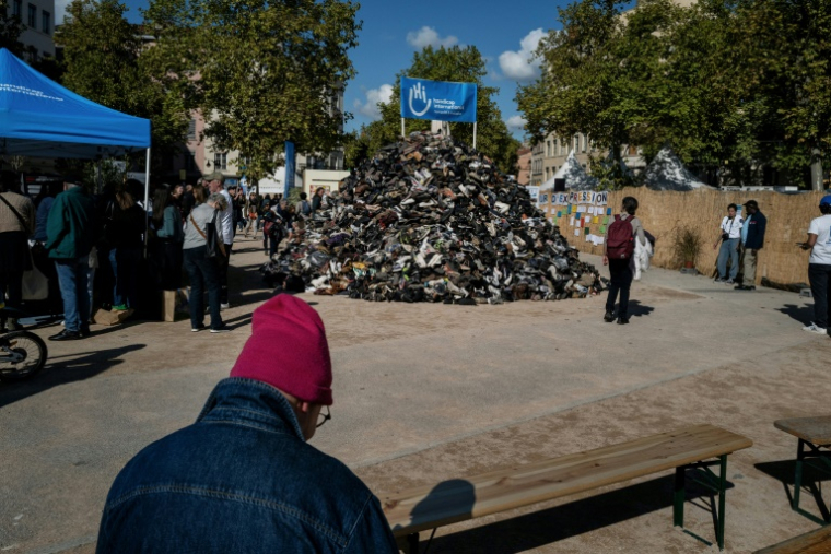 Des personnes autour d'une pyramide de chaussures organisée par Handicap international (HI) contre les mines antipersonnel, le 27 septembre 2025 à Lyon ( AFP / JEFF PACHOUD )