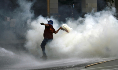 Un manifestant renvoie une grenade lacrymogène tirée par la police lors d'une manifestation devant le bâtiment du Parlement, où la réforme du travail du président argentin Javier Milei est examinée, à Buenos Aires, le 19 février 2026 ( AFP / Luis ROBAYO )