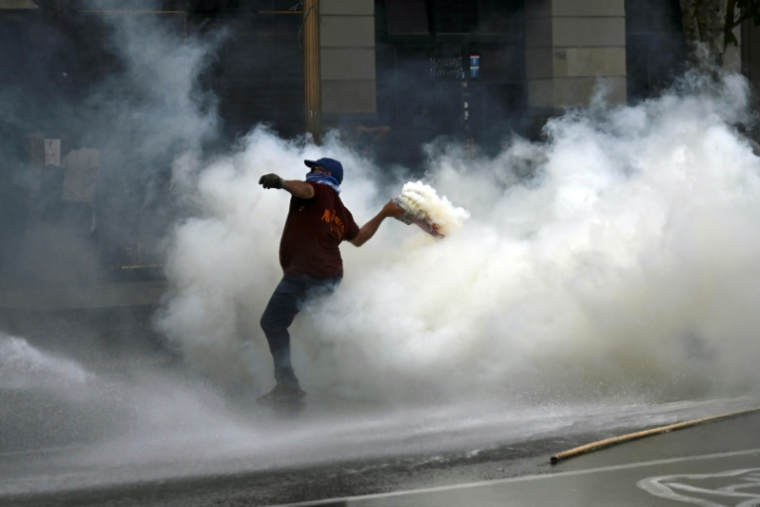 Un manifestant renvoie une grenade lacrymogène tirée par la police lors d'une manifestation devant le bâtiment du Parlement, où la réforme du travail du président argentin Javier Milei est examinée, à Buenos Aires, le 19 février 2026 ( AFP / Luis ROBAYO )