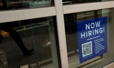 Un panneau d'embauche est visible dans la vitrine d'une entreprise aux États-Unis