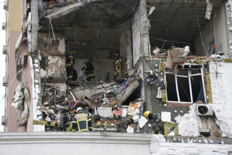 Des secouristes ukrainiens fouillent un bâtiment touché par une attaque de missiles et de drones russes, le 27 décembre 2025 à Kiev  ( AFP / Serhii Okunev )