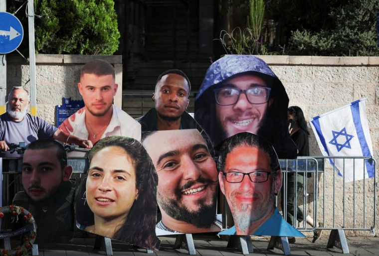 Une femme portant le drapeau israélien passe devant les affiches des otages tués lors de l'attaque meurtrière du 7 octobre par le groupe islamiste palestinien Hamas ou retenus en otage à Gaza