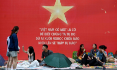 Des gens attendent et campent sur les trottoirs le 1er septembre 2025 à Hanoï avant le défilé militaire prévu mardi ( AFP / Nhac NGUYEN )