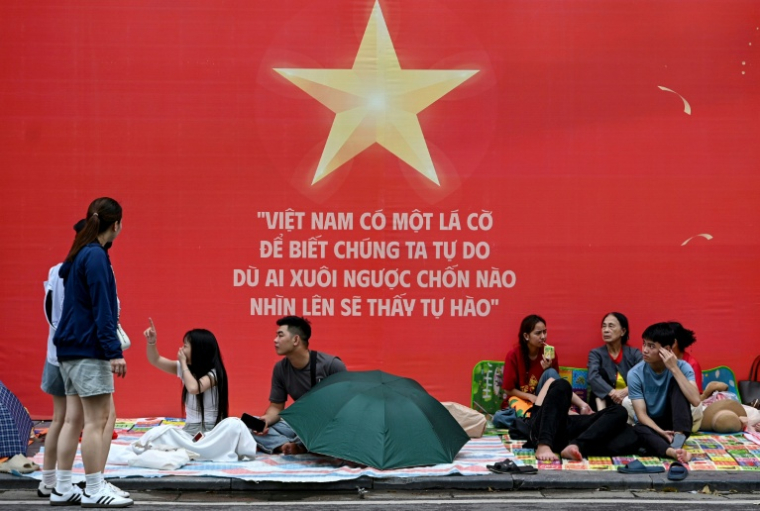 Des gens attendent et campent sur les trottoirs le 1er septembre 2025 à Hanoï avant le défilé militaire prévu mardi ( AFP / Nhac NGUYEN )