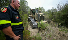 Un membre de la Sécurité civile se tient près d'un bulldozer qui élargit un sentier afin de faciliter l'accès des pompiers en cas d'incendie, le 8 août 2025 près de Talairan, dans l'Aude ( AFP / Bertrand GUAY )