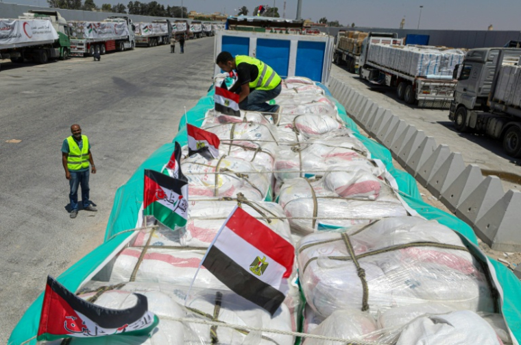 Des bénévoles vérifient des colis tandis que les camions chargés d'aide humanitaire attendent l'autorisation, du côté égyptien au point de passage de Rafah avec la bande de Gaza, d'entrer dans le territoire palestinien assiégé, le 6 août 2025 ( AFP / STR )