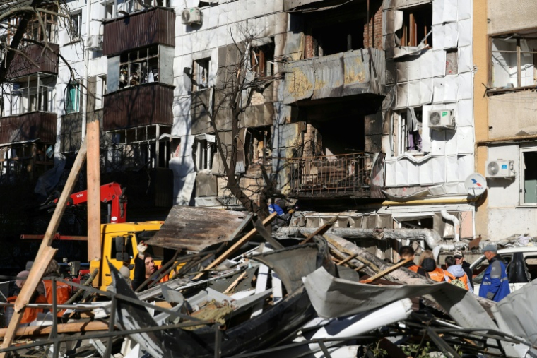 Des bénévoles et des employés municipaux débarrassent les gravats dans une zone résidentielle visée par attaque nocturne de drones dans la ville russe de  Belgorod, près de la frontière avec l'Ukraine, le 25 octobre 2026  ( AFP / STRINGER )