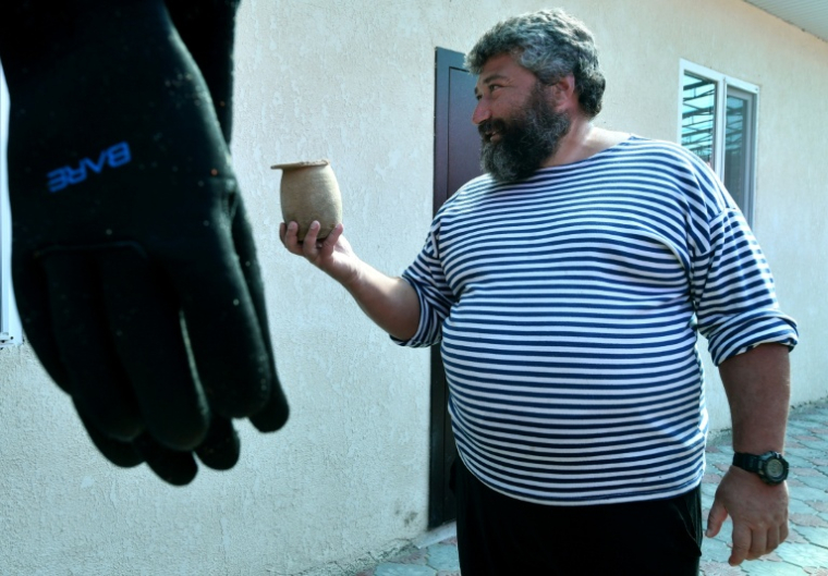 Maxime Menchikov, archéologue et directeur de l'expédition, tient des artefacts découverts sur le site sous-marin du fond du lac Issyk-Koul, près de la localité de Torou-Aïguyr au Kirghizistan, le 22 septembre 2026 ( AFP / Vyacheslav OSELEDKO )