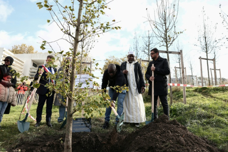 Le frère de Bouna, Siyakha (g) et son père Seydou (c) participent à la plantation d'un arbre près du lycée Robert Doisneau lors d'une cérémonie de commémoration marquant le 20e anniversaire de la mort des adolescents Zyed Benna et Bouna Traoré, à Clichy-sous-Bois, le 27 octobre 2025 en Seine-Saint-Denis ( AFP / Thibaud MORITZ )