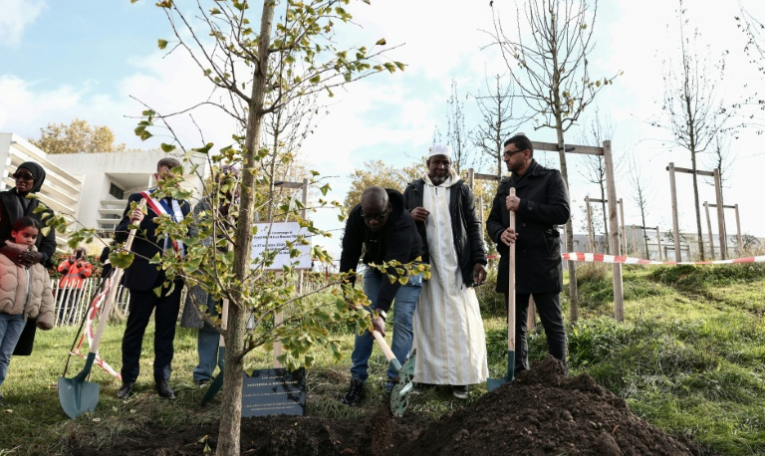 Le frère de Bouna, Siyakha (g) et son père Seydou (c) participent à la plantation d'un arbre près du lycée Robert Doisneau lors d'une cérémonie de commémoration marquant le 20e anniversaire de la mort des adolescents Zyed Benna et Bouna Traoré, à Clichy-sous-Bois, le 27 octobre 2025 en Seine-Saint-Denis ( AFP / Thibaud MORITZ )