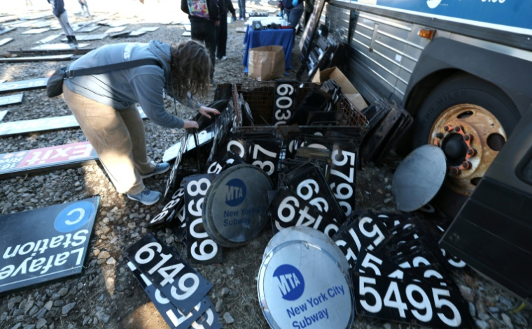 Une femme cherche parmi des panneaux du métro à l'occasion d'une vente annuelle organisée par la régie des transports de New York (MTA), le 9 octobre 2026. ( AFP / TIMOTHY A. CLARY )