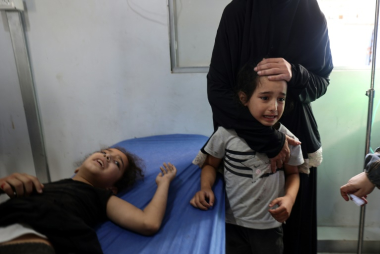 Une enfant palestinienne pleure près d'une fillette blessée recevant des soins à l'hôpital Al-Awda de Nousseirat, dans le centre de la bande de Gaza, après les frappes israéliennes, le 13 juillet 2025 ( AFP / Eyad BABA )
