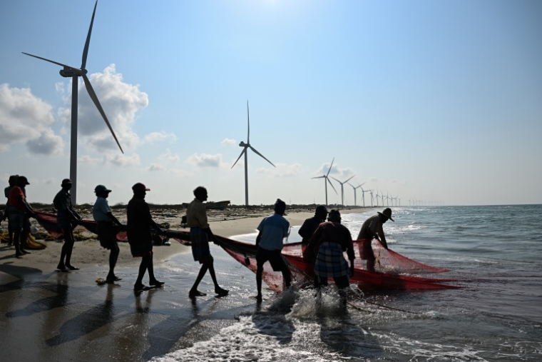 Cette photo, prise le 3 octobre 2026, montre des pêcheurs en train de pêcher sur une plage située près d'un parc éolien, sur la péninsule de Mannar, au Sri Lanka ( AFP / Ishara S. KODIKARA )