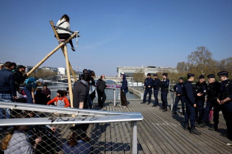 Des militants du groupe écologiste Extinction Rebellion (XR) occupent la passerelle Simone-de-Beauvoir à Paris, le 21 mars 2026 ( AFP / Kenzo TRIBOUILLARD )