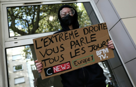 Un manifestant masqué tient une pancarte contre les chaînes de télévision CNews et BFMTV et la station de radio Europe 1 lors d'une manifestation contre la vie chère à Lille, le 17 octobre 2026 ( AFP / Sameer AL-DOUMY )