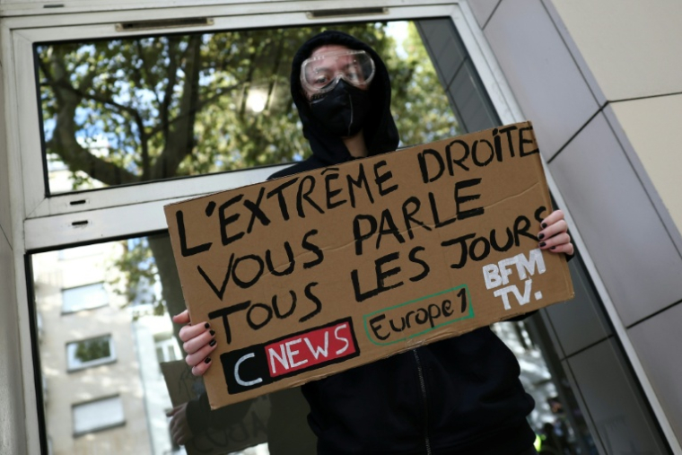 Un manifestant masqué tient une pancarte contre les chaînes de télévision CNews et BFMTV et la station de radio Europe 1 lors d'une manifestation contre la vie chère à Lille, le 17 octobre 2026 ( AFP / Sameer AL-DOUMY )