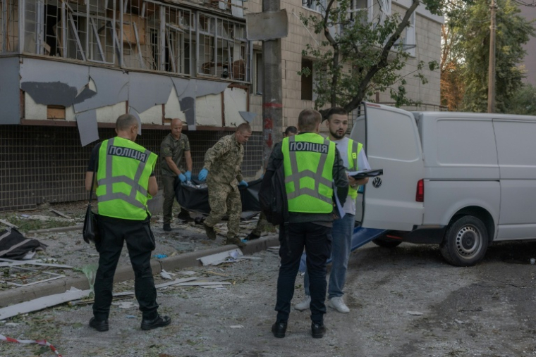 Le corps d'une victime est transporté dans un van à côté d'un immeuble résidentiel endommagé à la suite d'une frappe russe à Kiev, le 20 août 2026 ( AFP / Roman PILIPEY )