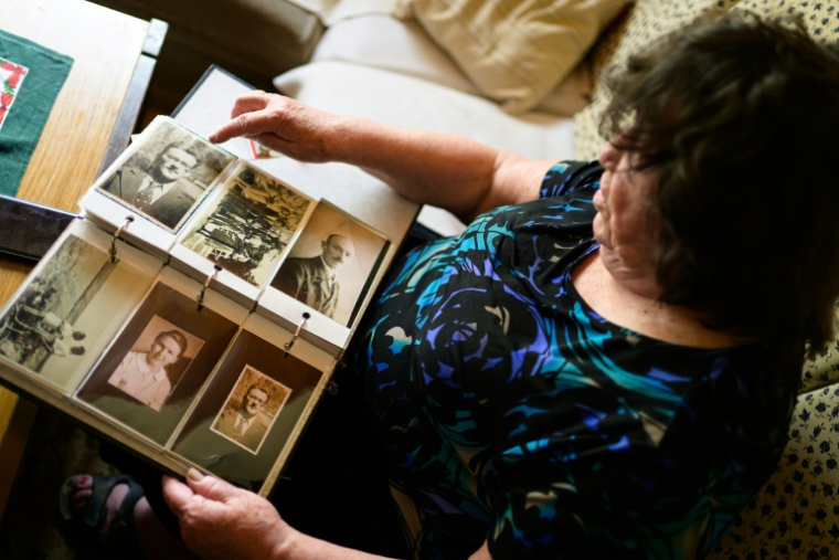 Blaza Cedilnik regarde des photos de son père, l'un des 15.000 "collabos" slovènes brutalement exécutés après-guerre, le 30 avril 2025 à Ljubljana, en Slovénie ( AFP / Jure Makovec )