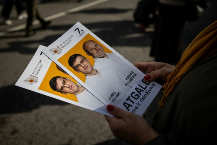 Une femme tient des tracts électoraux de Juris Vilums, candidat d'Apvienotais Saraksts (Liste unie), pendant la fête des moisssons à Rezekne, en Lettonie, le 27 septembre 2026 ( AFP / Wojtek RADWANSKI )