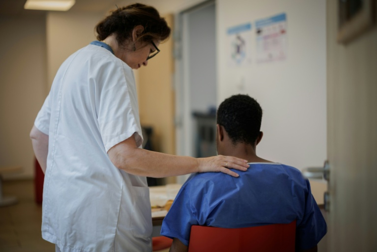 Une aide-soignante encourage un patient en salle des repas du Centre renforcé d'urgences psychiatriques de l'hôpital Delafontaine à Saint-Denis en Seine-Saint-Denis le 17 juin 2026 ( AFP / Simon WOHLFAHRT )