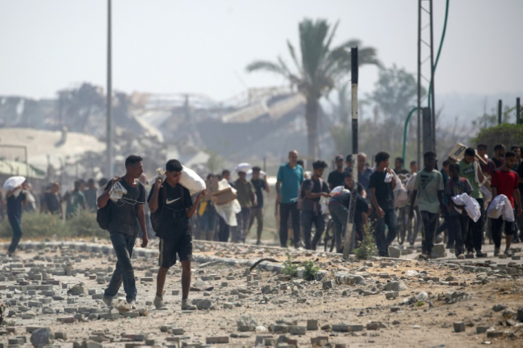 Des déplacés palestiniens portent des produits alimentaires obtenus à un point de distribution du centre de la bande de Gaza, le 26 juillet 2025 ( AFP / Eyad BABA )