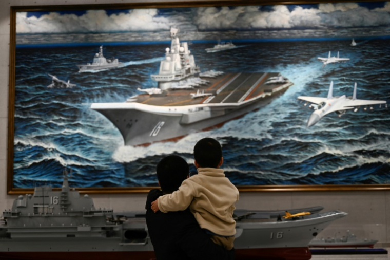 Une maquette et une peinture du porte-avions chinois Liaoning au Musée militaire de Pékin le 2 mars 2025 ( AFP / Pedro PARDO )