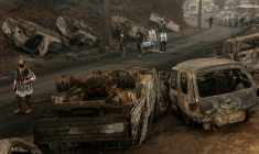 Des habitants marchent dans une rue jonchée de carcasses calcinées de véhicules après qu'un incendie de forêt a ravagé Lirquen, près de Concepcion, au Chili, le 20 janvier 2026 ( AFP / Raul BRAVO )