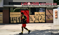 Un passant devant des commerces barricadés et recouverts de graffitis, dans le centre-ville de Los Angeles, le 17 juin 2025 ( AFP / Frederic J. BROWN )