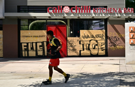Un passant devant des commerces barricadés et recouverts de graffitis, dans le centre-ville de Los Angeles, le 17 juin 2025 ( AFP / Frederic J. BROWN )