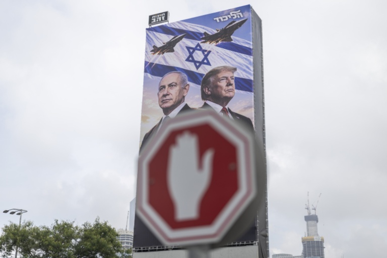 Une grande affiche représentant le Premier ministre israélien Benjamin Netanyahou et le président américain Donald Trump, derrière un panneau stop à Tel-Aviv, le 26 octobre 2026 ( AFP / Ilia YEFIMOVICH )