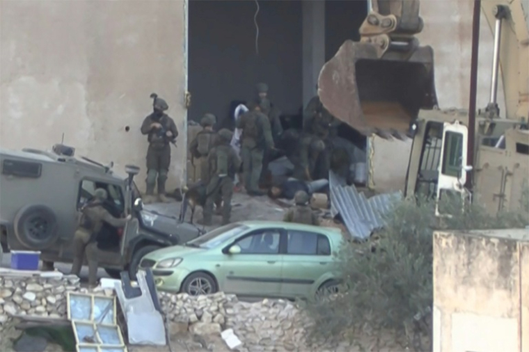 Image tirée d'une vidéo d'AFPTV, le 27 novembre 2025, montrant des soldats israéliens entourant le corps de l'un des deux Palestiniens abattus après s'être apparemment rendus aux forces israéliennes lors d'une opération militaire à Jénine, en Cisjordanie occupée ( AFPTV / STRINGER )