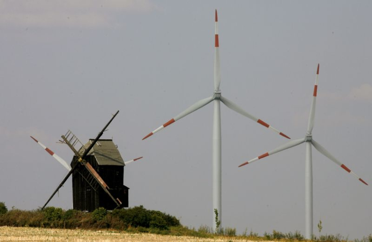 Un vieux moulin à vent se dresse devant les turbines d'un parc éolien près du village d'Ostingerslebe