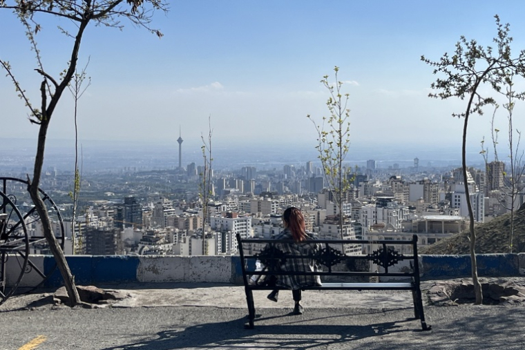 Une femme est assise sur un banc donnant sur la ville, au parc Pardisan à Téhéran, le 22 avril 2026. ( AFP / - )