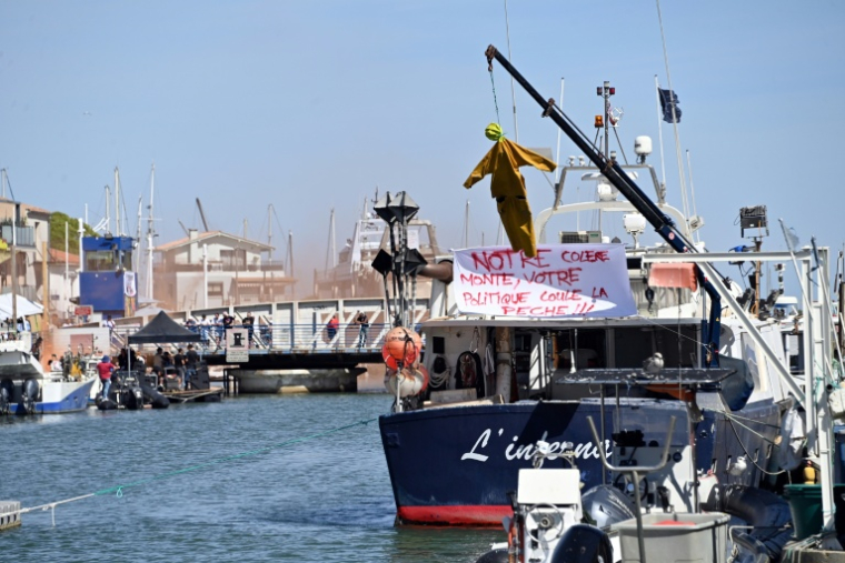 Une effigie suspendue à une grue, à côté d'une banderole, sur un bateau au port du Grau-du-Roi, lors d'une manifestation de pêcheurs contre la flambée des prix du carburant, le 17 septembre 2026 dans le Gard ( AFP / Sylvain THOMAS )