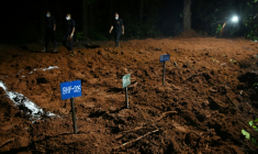Des agents de police marchent à proximité de tombes de victimes non identifiées de la crue dévastatrice, le 30 août 2026 à Devghat au Népal ( AFP / Prakash MATHEMA )